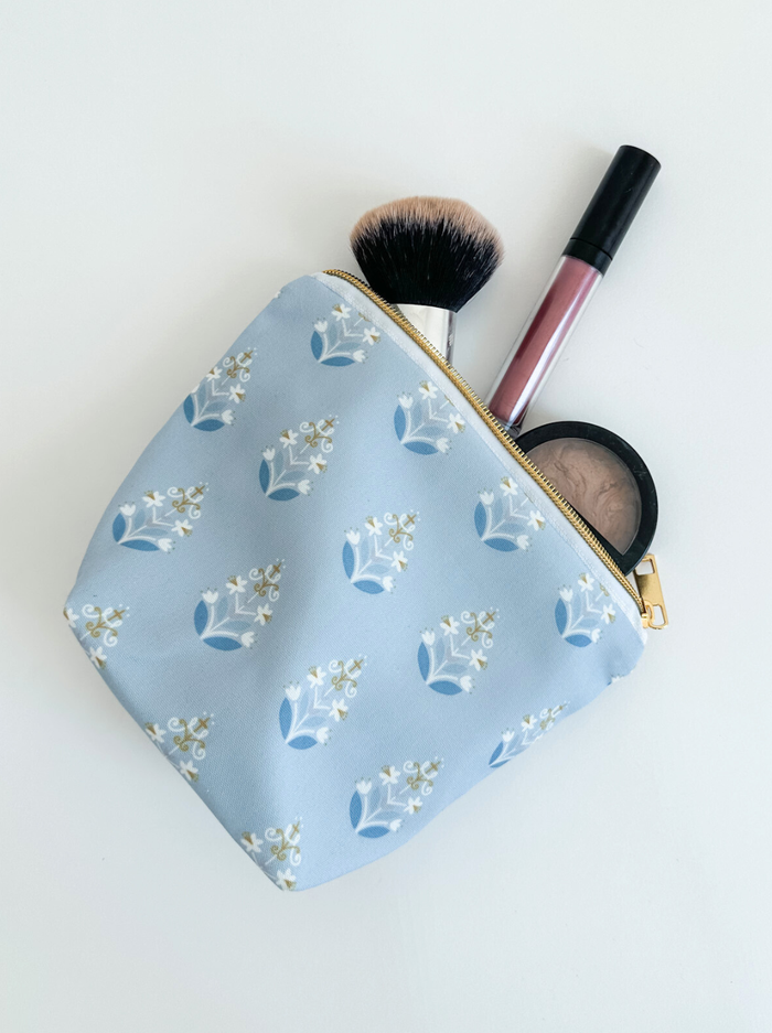 Blue pattern cosmetic bag with makeup on white background