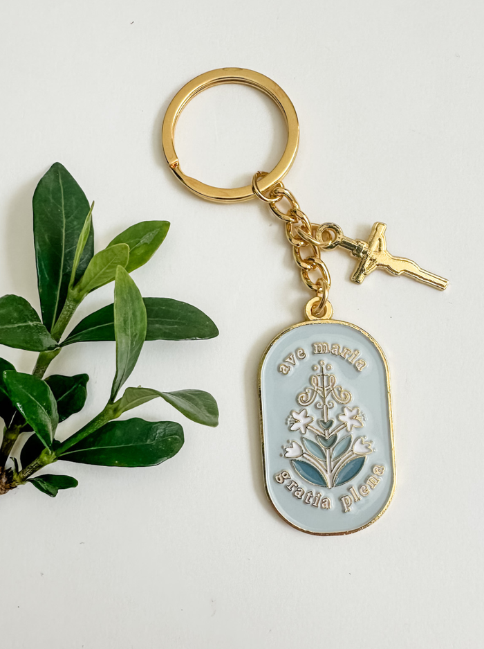 Gold keychain with white and floral design by plant