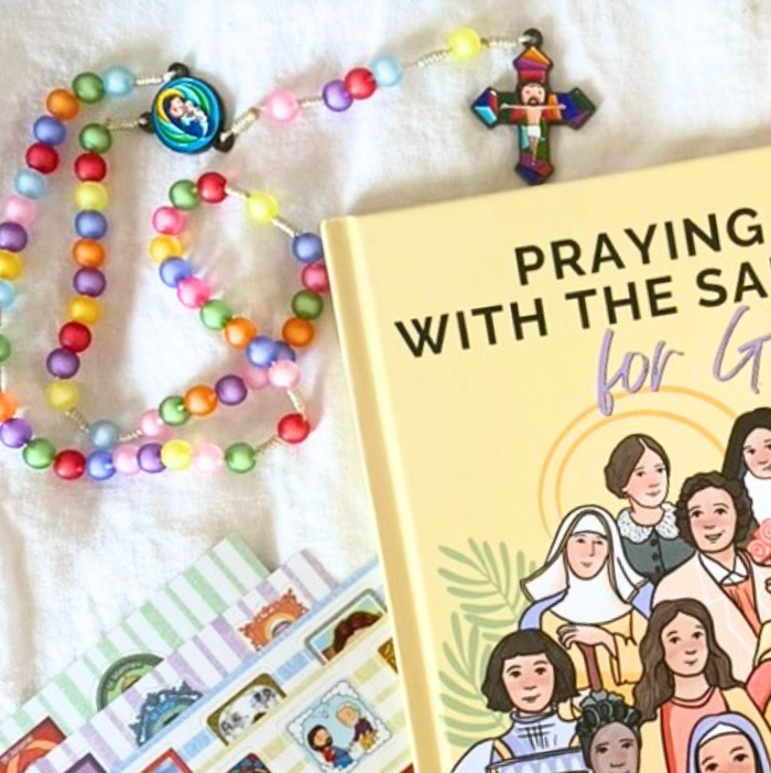 Colorful rosary with a book titled 'Praying with the Saints for Girls' on a white background