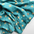 Teal fabric with gold star patterns on a white background