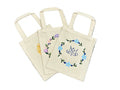 Set of tote bags with floral designs on a textured surface.