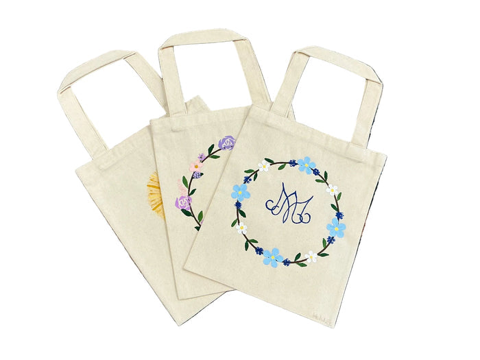 Set of tote bags with floral designs on a textured surface.