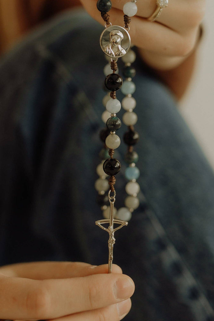 Person holding a rosary with a blurred background