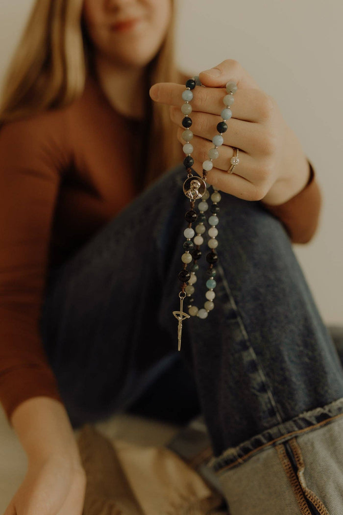 Person holding a rosary with a blurred background