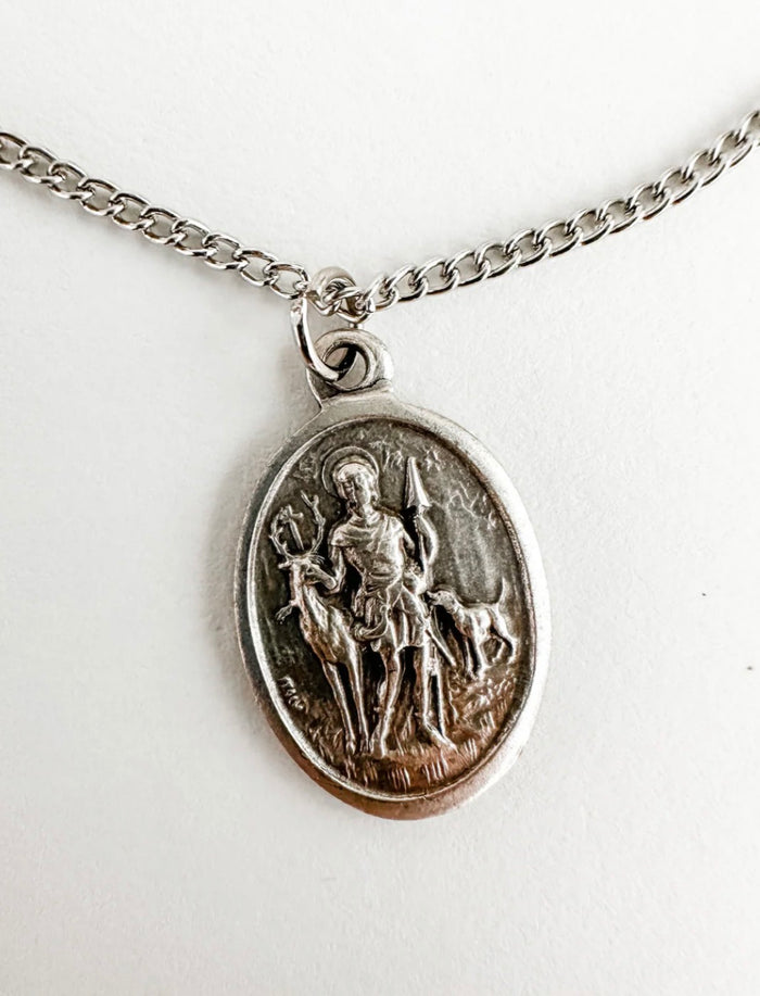 Silver pendant necklace with an engraved design on a white background