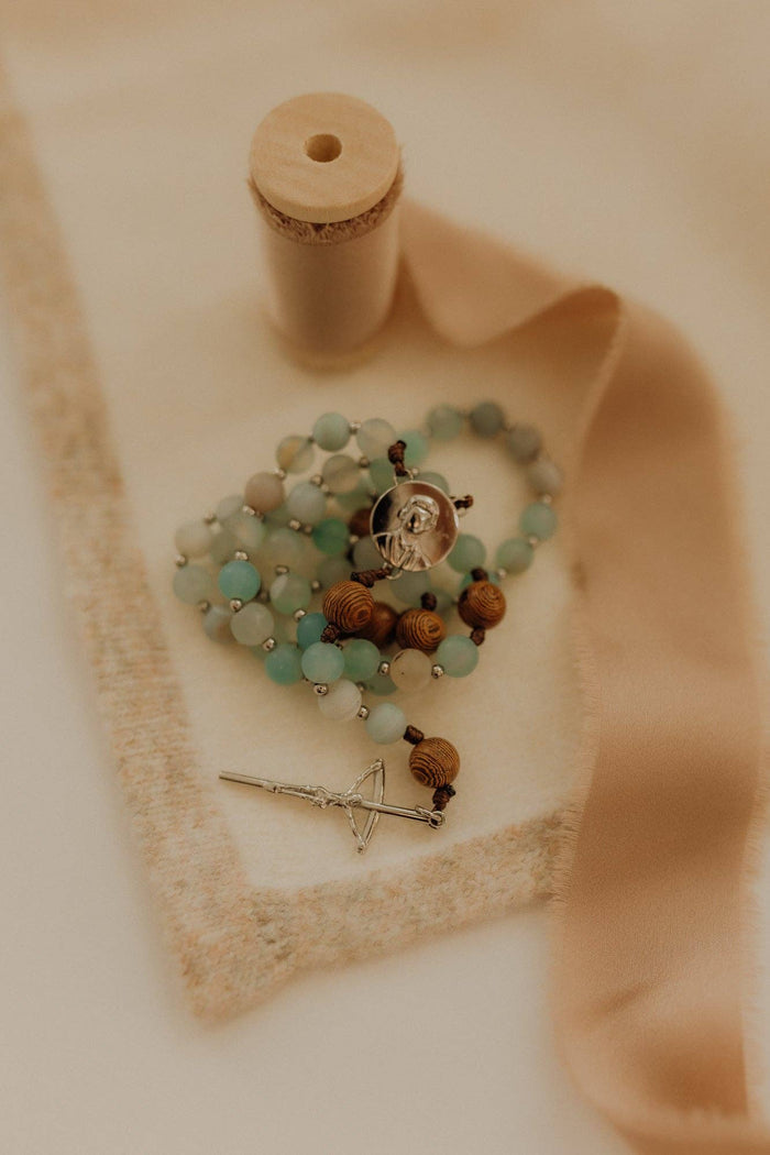 Beaded rosary with a key charm on a beige fabric background