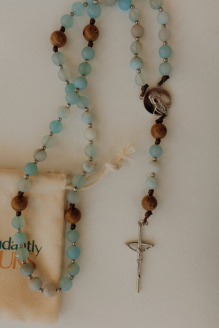 Turquoise beaded rosary with a cross pendant on a white background