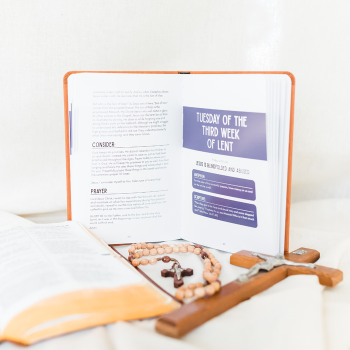 Open book with religious items on a white surface
