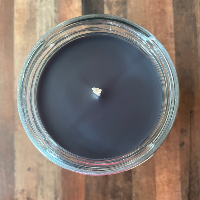 Dark candle in a glass jar on a wooden surface